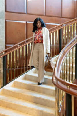 Model walking down the circular stair wearing white cardigan and pants