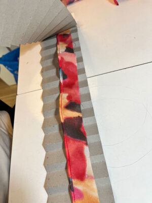 laying a strip of fabric onto cardboard pleating mould