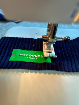 sewing green label to navy corduroy jacket's lining